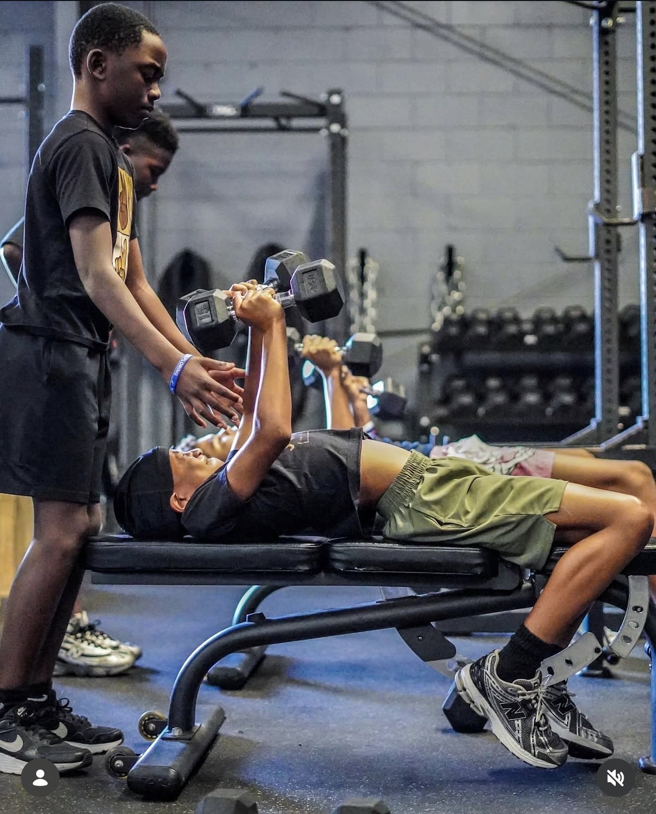 Young athlete bench pressing while a coach spots the bar